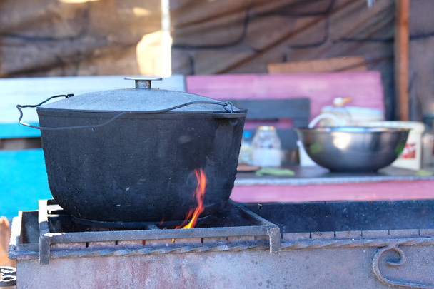 Étel főzés outdoorson nyitott konyha öntöttvas edényben. Utcai élelmiszer grill. - Fotó, kép