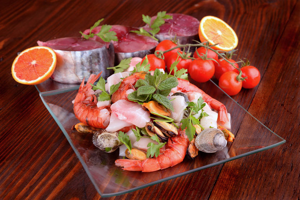 γυάλινα πιάτα με ψάρι παλαμίδα μαλάκια και οστρακοειδή raw στο ξύλινο ταμπλό - Φωτογραφία, εικόνα