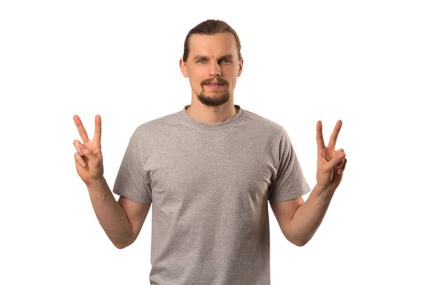Bearded attractive caucasian guy hoding hands with victory sign isolated on white background - Valokuva, kuva