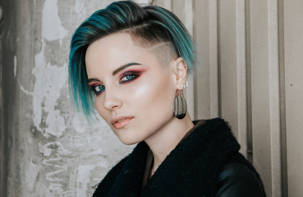 Fashionable young girl with blue hair and smokey eyes make up standing in front of industrial building - Φωτογραφία, εικόνα