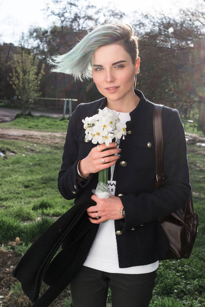 Mladá dívka s květinami na ulici na jarní či letní sezóně. - Fotografie, Obrázek
