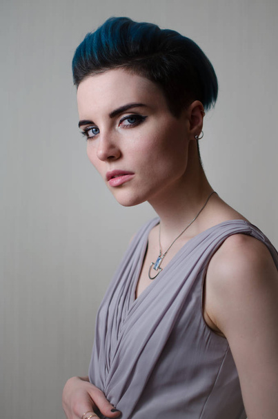 Strong,beautiful,elegant woman in long dress dress, with short blue hair and beautiful face,looks with attitude at camera. - Фото, зображення