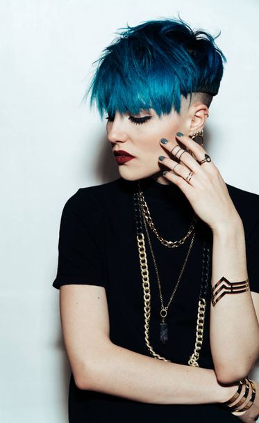 fashion photography of a girl with blue hair on a white background looking directly at the camera. Thick yellow chain and bijouterieher on her neck. Professional model posing in studio - Photo, image