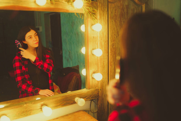 Young woman looking at himself in mirror in dressing room. Beautiful sensuality girl posing in stylish room. - Фото, зображення