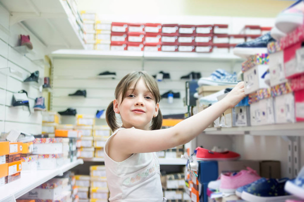   lány hét éves kiválasztása nyári cipő áruház. - Fotó, kép