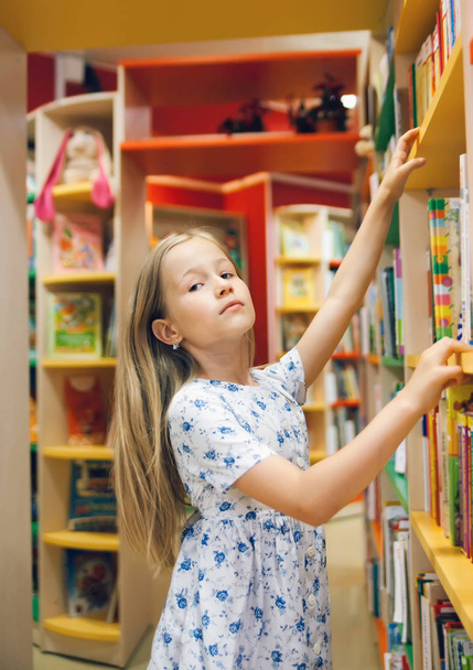  όμορφο κορίτσι του σχολείου στη βιβλιοθήκη επιλέγοντας βιβλία.  - Φωτογραφία, εικόνα