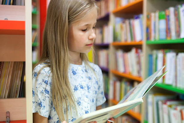  school girl reading   book in     library.  - Фото, изображение