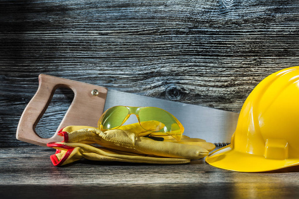 glasses on gloves and handsaw with helmet - Photo, Image