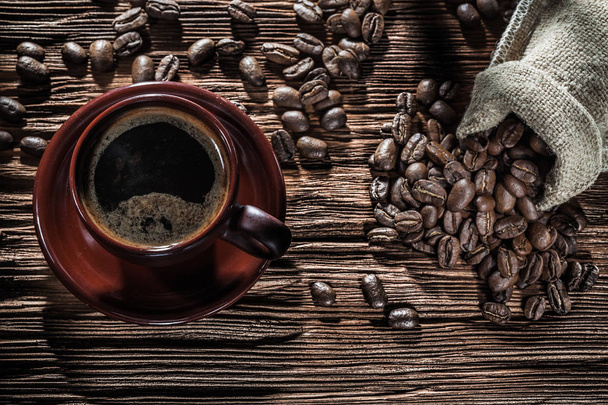 coffee cup and sack with beans on vintage wood board - Fotó, kép