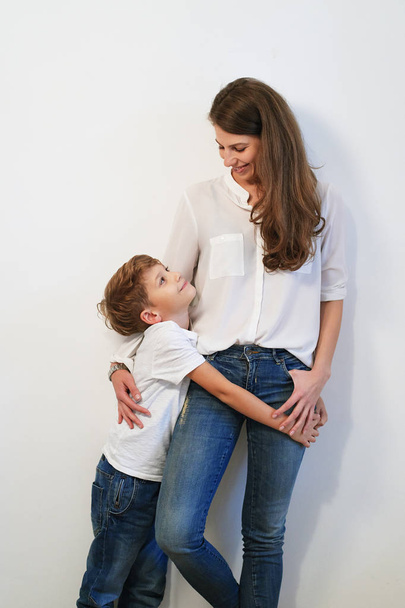 Bella giovane madre con figlio che abbraccia su sfondo bianco
 - Foto, immagini
