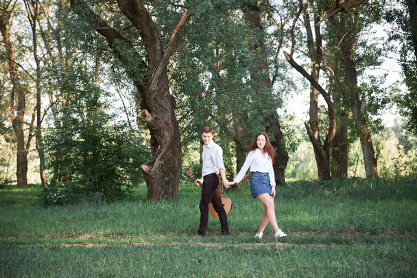 mladý pár, procházky v lese a hraje kytara, letní přírody, světlo, stíny a zelené listy, romantické pocity - Fotografie, Obrázek