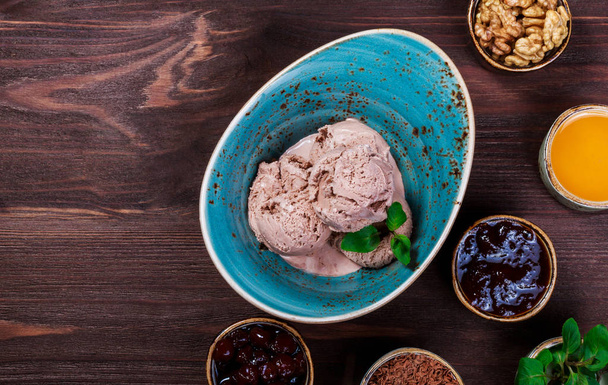 Cuillères de crème glacée au chocolat dans un bol avec des feuilles de menthe sur fond en bois. Vue du dessus
 - Photo, image