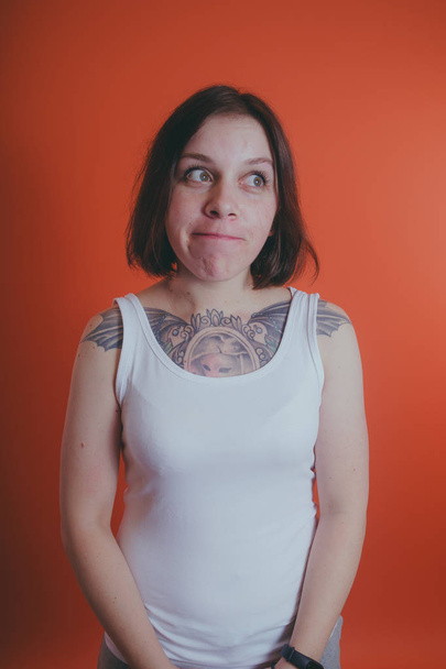 Girl with a tattoo on her chest, posing on an orange background - Fotó, kép