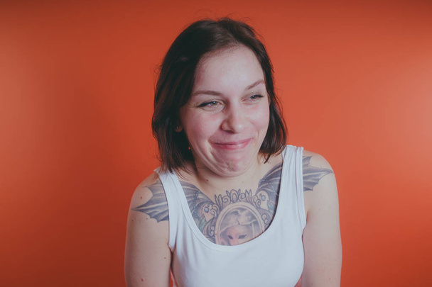 Girl with a tattoo on her chest, posing on an orange background - Valokuva, kuva