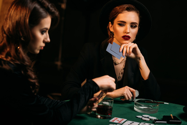 attractive girls playing poker together at table in casino - Фото, зображення