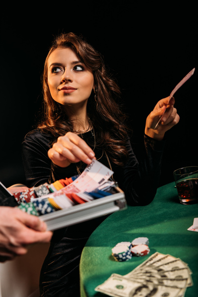 beautiful cheerful woman taking euro banknotes from box at table in casino - Foto, Bild