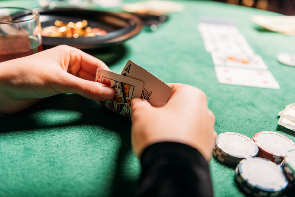 カジノのテーブルでポーカーのカードを保持している女の子の画像をトリミング - 写真・画像