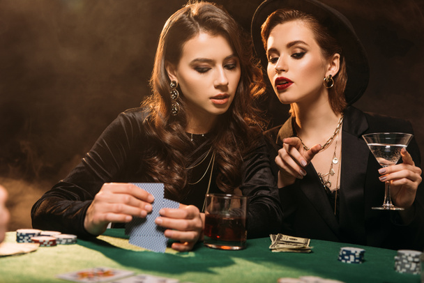 chicas atractivas jugando al póquer en la mesa en el casino, mujer señalando algo a un amigo
 - Foto, Imagen