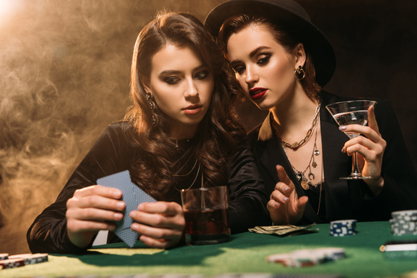 attractive girls playing poker together at table in casino - Photo, Image