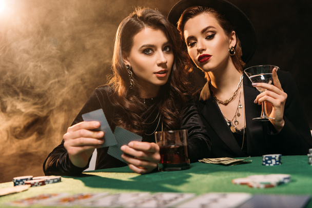 привлекательные девушки играют в покер за столом в казино
 - Фото, изображение