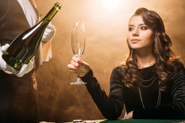 Kellner gießt Champagner ins Glas für schönes Mädchen am Pokertisch im Casino - Foto, Bild