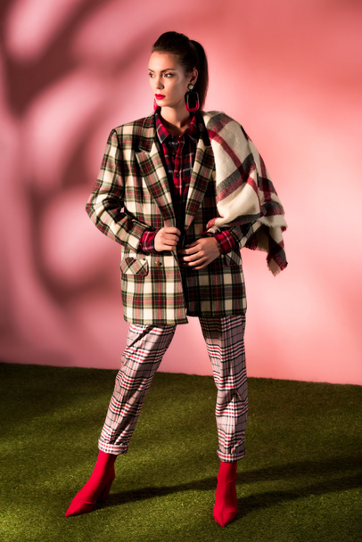 beautiful model posing in checkered suit on pink background - Foto, afbeelding