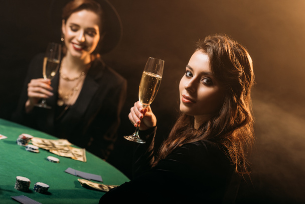 atraktivní holky držení sklenice šampaňského u pokerového stolu v kasinu - Fotografie, Obrázek