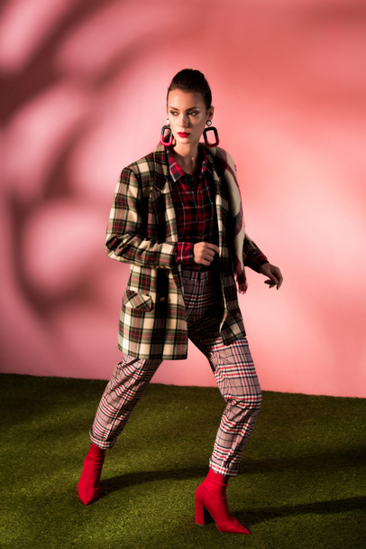 beautiful stylish model posing in checkered suit on pink background - 写真・画像