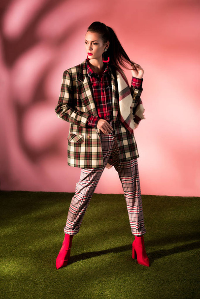 attractive woman posing in autumn checkered suit on pink background - Foto, afbeelding