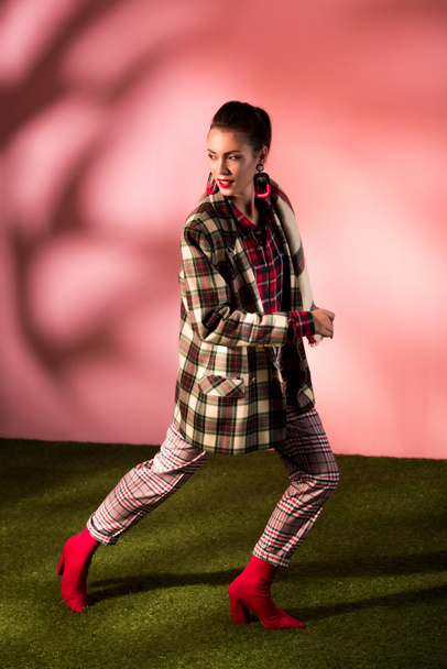 beautiful young woman posing in checkered suit on pink background - Valokuva, kuva