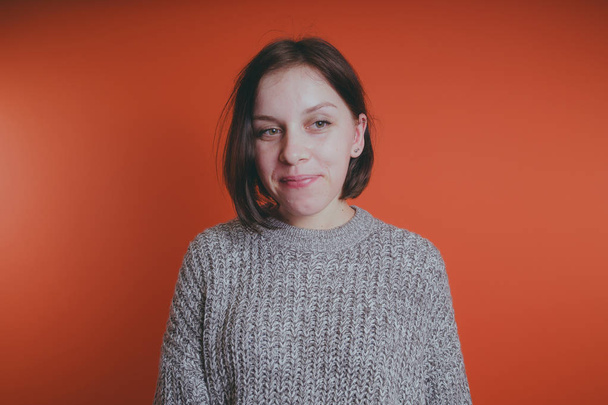 Young girl in warm grey sweater posing on orange background, woman with short haircut in knitted sweater, space for text - Photo, image