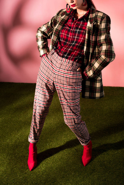 cropped view of fashionable woman posing in checkered suit on pink background - Photo, Image