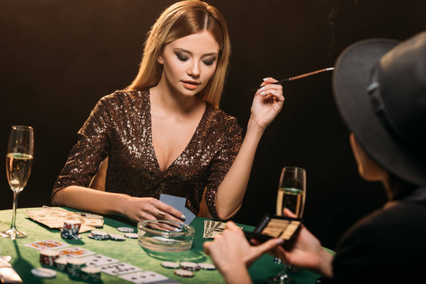 chicas atractivas fumar cigarrillos y jugar al póquer en la mesa en el casino
 - Foto, Imagen