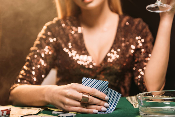 körülvágott kép girl gazdaság üveg és a póker, kaszinó asztal - Fotó, kép