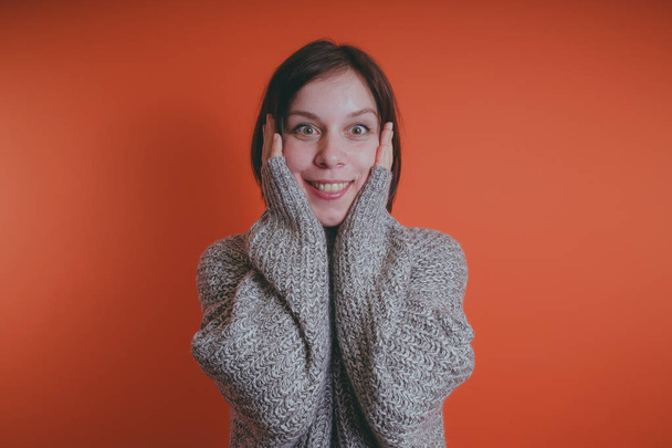 Young girl in warm grey sweater posing on orange background, woman with short haircut in knitted sweater, space for text - Fotoğraf, Görsel