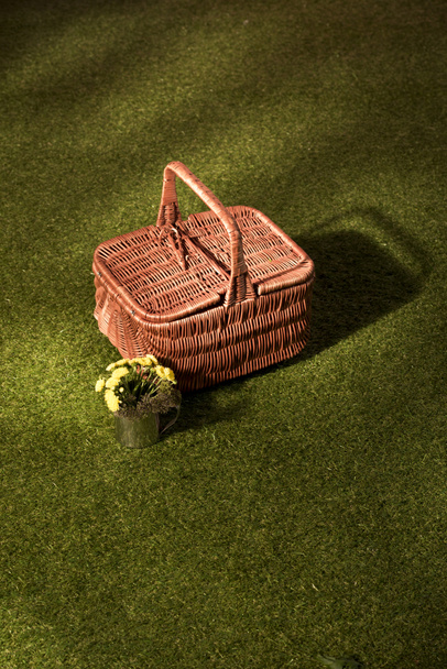 flowers and wicker basket for picnic on green grass - Photo, Image