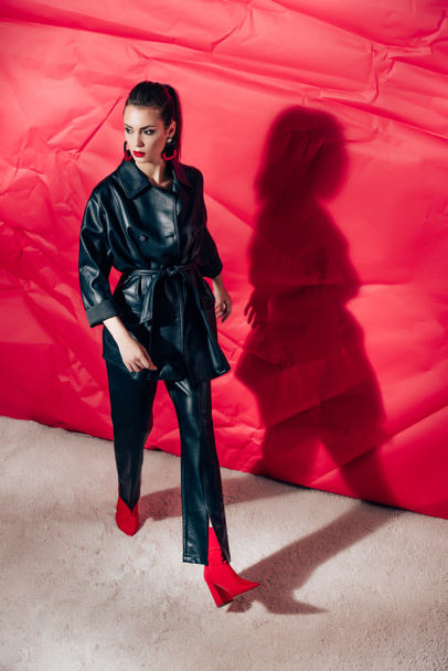 attractive model posing in black leather suit on red background - Φωτογραφία, εικόνα