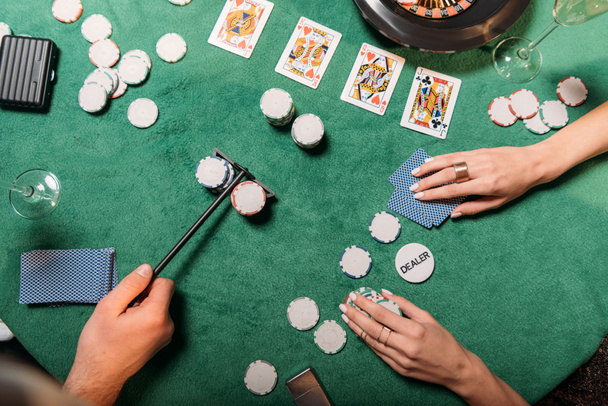 обрезанный образ девушки и крупье, играющих в покер за столом в казино
 - Фото, изображение