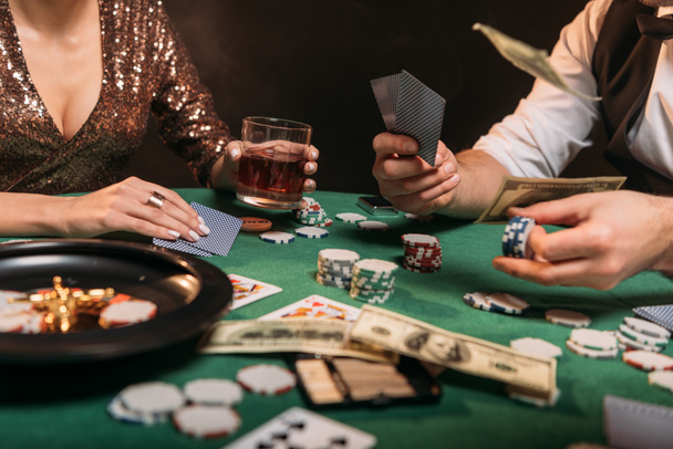 περικομμένη εικόνα μιας γυναίκας κι ενός κρουπιέρης παίζοντας πόκερ στο τραπέζι στο καζίνο - Φωτογραφία, εικόνα