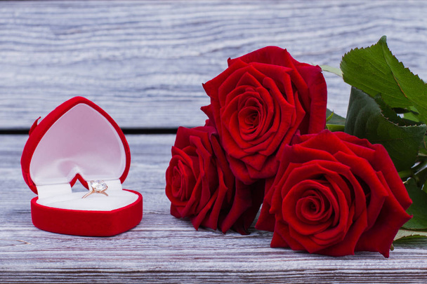 Κόκκινα τριαντάφυλλα και διαμαντένιο δαχτυλίδι στο πλαίσιο. - Φωτογραφία, εικόνα