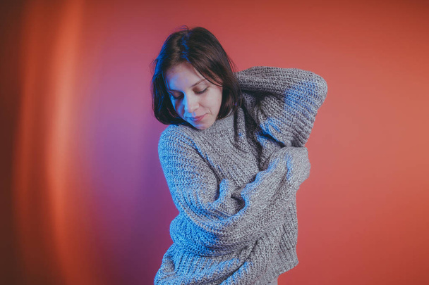 Young girl in warm grey sweater posing on orange background, woman with short haircut in knitted sweater, space for text - Foto, Imagem