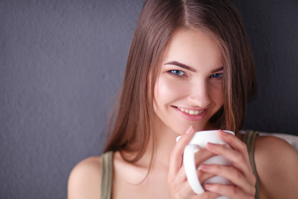 Young woman resting on couch and drinking tea in room - Foto, Imagen