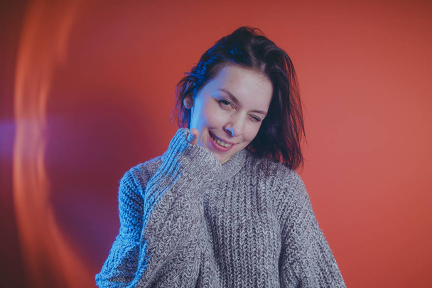 Young girl in warm grey sweater posing on orange background, woman with short haircut in knitted sweater, space for text - Фото, зображення