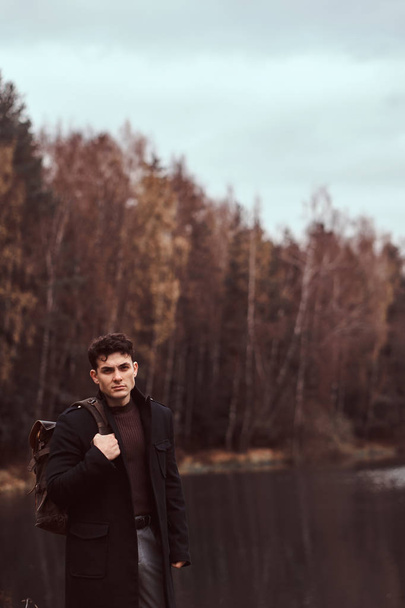 Przystojny, młody turysta, stojący w pobliżu jeziora, w lesie jesienią. - Zdjęcie, obraz