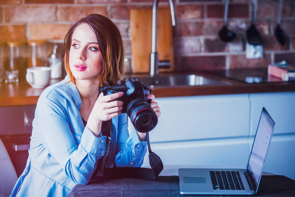 Beautiful young photographer sitting at kitchen with camera. Concept of work with startup business - Photo, Image
