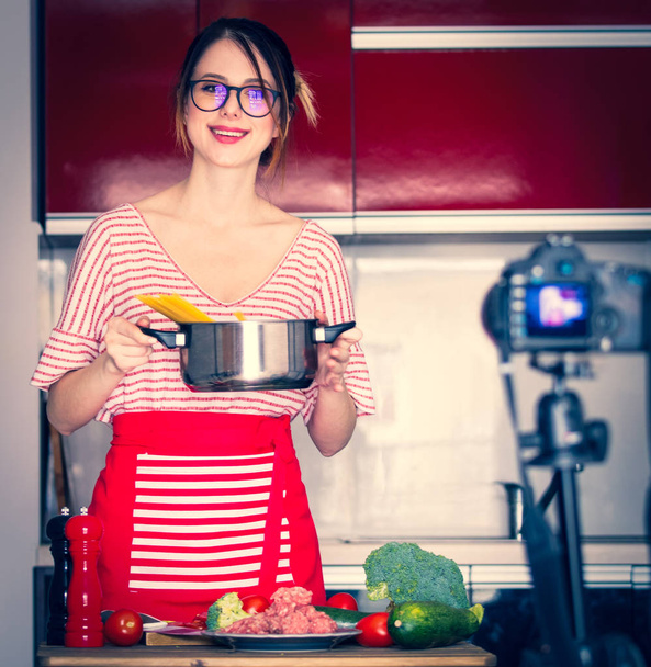 Młody blogger kaukaski kobieta gotowania w aparat fotograficzny pod kątem wideo dzielenie witryny. Pozycja domu w kuchni  - Zdjęcie, obraz