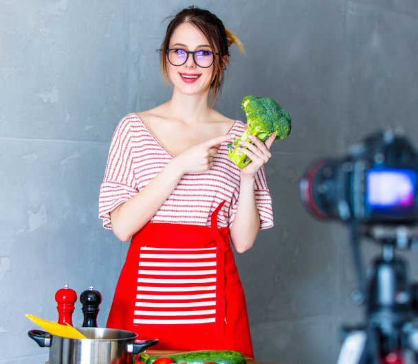 ビーガン料理のビデオ共有のウェブサイトのためのカメラで若い白人ブロガーの女性。キッチンでホームの場所 - 写真・画像