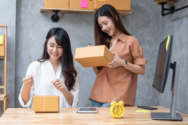 zwei junge asiatische Frauen starten Kleinunternehmer sme Distributionslager mit Paketbriefkasten. Kleineigentümer Home Office. Online-Marketing und Produktverpackung und Lieferservice - Foto, Bild