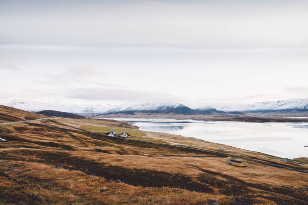Село з господарств у сільській місцевості горами Ісландії, snowy гори на задньому плані. - Фото, зображення