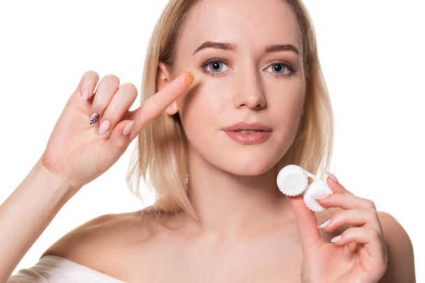 Young woman holding contact lenses cases and lens in front of her face on white background - Fotó, kép